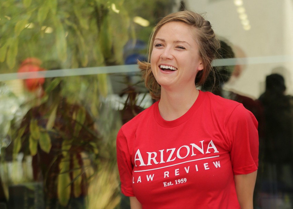 Woman in red Arizona Law Review t-shirt smiles outside the law school building