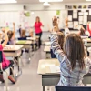 kids in class with their hands raised 